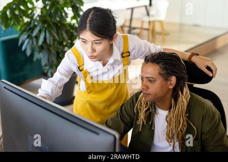 Diversi colleghi di lavoro occasionali che usano il computer per discutere di lavoro alla scrivania in ufficio. Lavoro di squadra, lavoro, affari, comunicazione e ufficio informale, unalte Foto Stock