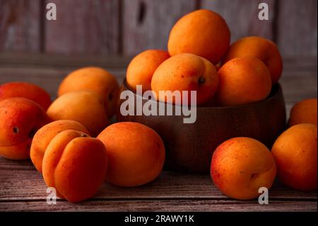 Albicocche mature in un recipiente di legno su sfondo di legno Foto Stock