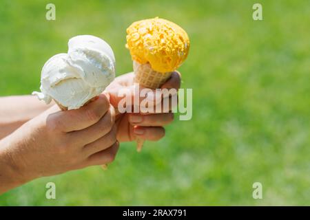 Le mani delle donne tengono un gelato rinfrescante in coni di waffle con un pizzico di saporito sapore di limone. Con spazio di copia Foto Stock