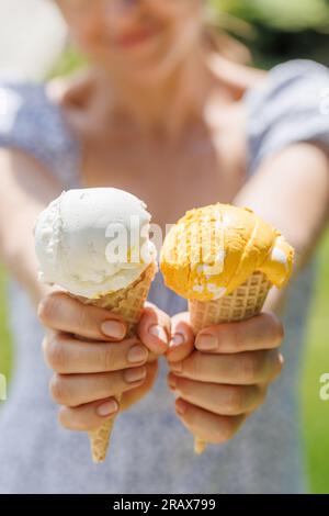 Le mani delle donne tengono un gelato rinfrescante in coni di waffle con un pizzico di saporito sapore di limone Foto Stock