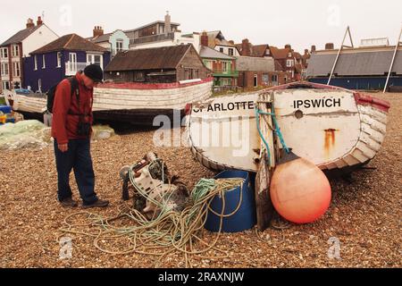 Barca, Charlotte di Ipswich, un motore per barche Lister, corde, una spiaggia di ciottoli, un uomo e proprietà sul mare ad Aldeburgh, Suffolk. REGNO UNITO Foto Stock