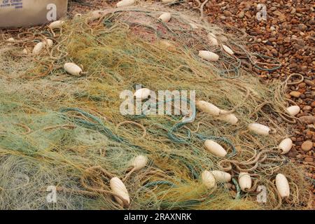 Pila di rete da pesca commerciale da traino molto fine e trasparente e galleggianti sulla spiaggia rocciosa di Aldeburgh, Suffolk Foto Stock