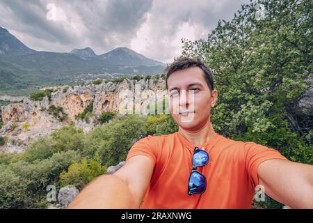 Buon escursionista o scalatore che scatta foto di selfie su un sentiero in montagna con le famose rocce di Geyikbayiri e canyon sullo sfondo Foto Stock