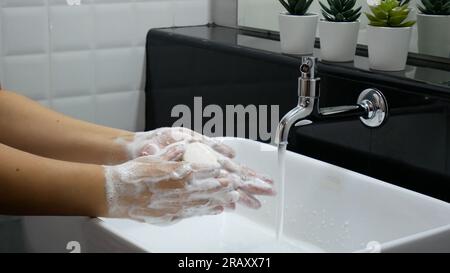 igiene personale. lavare le mani, strofinare accuratamente la mano con sapone che ha molte bolle per la pulizia e la disinfezione al lavandino in bagno. Foto Stock