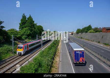 Trasporto per il treno del Galles che viaggia su binari che corrono lungo una strada a Salford, in Inghilterra. Foto Stock