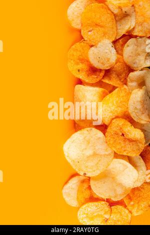 Bordo delle patatine isolate su sfondo arancione. Goccia appetitosa ricoperta con un condimento saporito e speziato Foto Stock