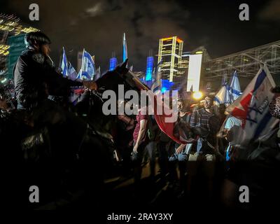 Tel Aviv, Israele. 6 luglio 2023. Un protestore israeliano si trova tra gli agenti di polizia a cavallo durante una manifestazione. Migliaia di manifestanti bloccarono l'autostrada principale di Tel Aviv, le strade principali e gli incroci attraverso Israele in uno spontaneo sfogo di rabbia a seguito delle dimissioni forzate del popolare capo della polizia della città. (Foto di Eyal Warshavsky/SOPA Images/Sipa USA) credito: SIPA USA/Alamy Live News Foto Stock