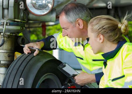 ingegnere che controlla il battistrada sul carrello di atterraggio dell'aeromobile Foto Stock