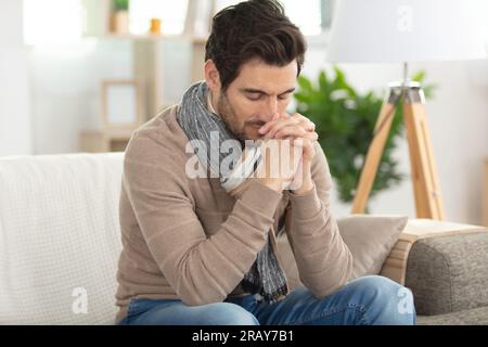 un uomo triste con gli occhi chiusi che prega con la speranza Foto Stock