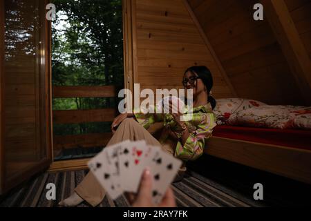 Vivi l'emozione di un gioco di carte con questa immagine accattivante. Un primo piano rivela la mano di una donna in possesso di una carta da gioco, mostrando il Foto Stock