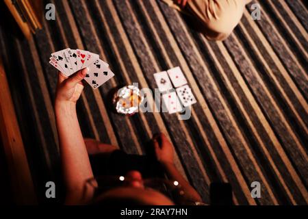 Vivi l'emozione di un gioco di carte con questa immagine accattivante. Un primo piano rivela la mano di una donna in possesso di una carta da gioco, mostrando il Foto Stock