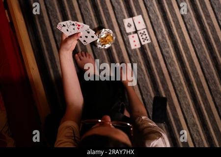 Vivi l'emozione di un gioco di carte con questa immagine accattivante. Un primo piano rivela la mano di una donna in possesso di una carta da gioco, mostrando il Foto Stock