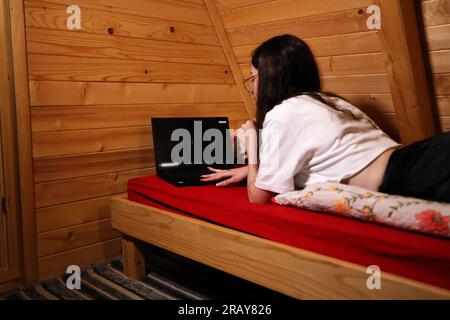 Assisti all'era moderna dell'istruzione online quando una giovane donna felice lavora sul suo notebook a letto Foto Stock