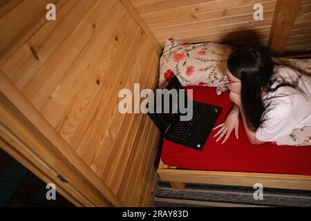 Assisti all'era moderna dell'istruzione online quando una giovane donna felice lavora sul suo notebook a letto Foto Stock