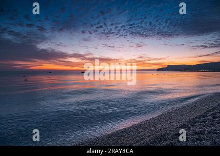 la bellezza mozzafiato della natura mentre le vivaci sfumature dipingono il cielo durante un'ipnotizzante alba sulla spiaggia del mare Foto Stock
