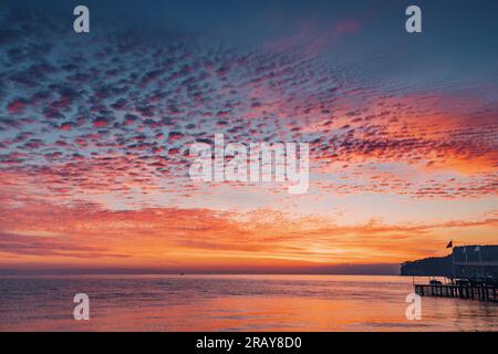 nuova alba con una vibrante alba sulla spiaggia del mare, dove i colori vivaci illuminano l'orizzonte e risvegliano i sensi. Foto Stock