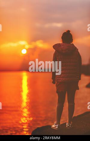 Le ragazzine ammirano un incredibile tramonto sul lago di Ginevra, Losanna, Svizzera. Vista posteriore, immagine opaca Foto Stock