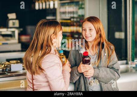 Due bambine che comprano da bere in bottiglie di plastica Foto Stock