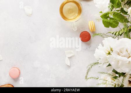 Impostazione estetica del tavolo. Teiera verde alle erbe, tazza, dessert con macaron, stile di vita con fiori bianchi. Estetica femminile, tempo meditativo per te stesso, accogliente h Foto Stock