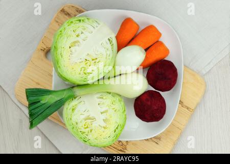 Cavolo, carote, barbabietole e cipolle in un piatto. Verdure sbucciate per cucinare in casa. Cibo sano fatto in casa. Foto Stock