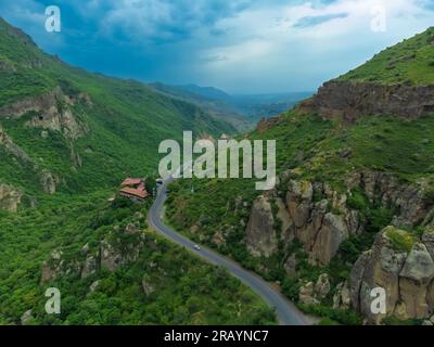 Vista sui droni della strada in montagna con un piccolo ristorante. Bellissimo paesaggio con una strada in montagna. Viaggi Foto Stock
