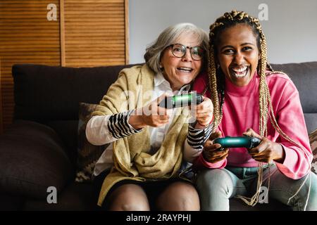 Donne felici e multi-generazionali che si divertono a giocare ai videogame insieme a casa Foto Stock