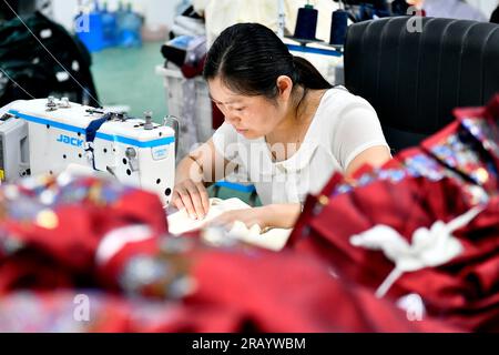 Caoxian, provincia cinese di Shandong. 6 luglio 2023. Un membro dello staff lavora in una fabbrica di Hanfu a Caoxian, nella provincia di Shandong, nella Cina orientale, il 6 luglio 2023. La contea di Caoxian ha sviluppato una catena industriale completa di Hanfu negli ultimi anni. Attualmente, ci sono più di 2.100 imprese collegate a Hanfu nella contea. Le vendite di Hanfu a Caoxian hanno raggiunto quasi 4 miliardi di yuan (circa 552 milioni di dollari) nella prima metà di quest'anno. Crediti: Guo Xulei/Xinhua/Alamy Live News Foto Stock