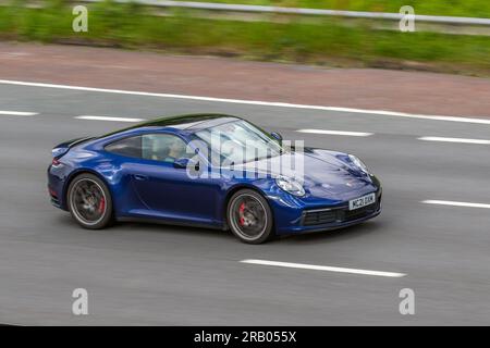 2021 Blue Porsche 911 Carrera 4S, T 450 4S Start/Stop Coupé benzina 2981 cc, trazione integrale; viaggia a velocità sostenuta sull'autostrada M6 a Greater Manchester, Regno Unito Foto Stock