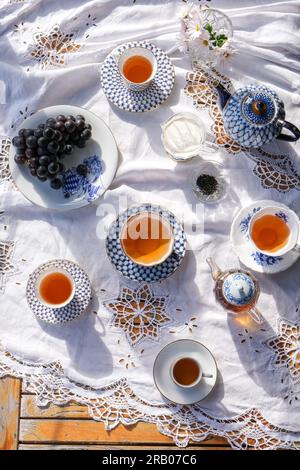 Set da tè su una tovaglia di pizzo bianco al sole estivo Foto Stock