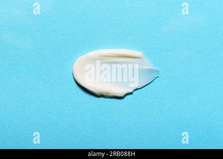 Campione naturale di crema bianca biologica su sfondo blu. Foto Stock