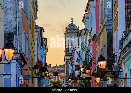 Strada con case storiche con le loro facciate e lanterne nel quartiere Pelourinho a Salvador durante il tramonto Foto Stock