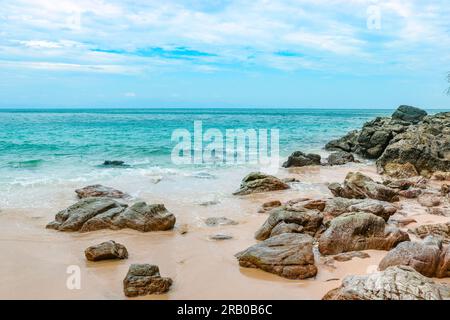 Spiaggia rocciosa di sabbia tropicale su un'isola deserta con acque cristalline. Romanticismo e avventura. Foto Stock