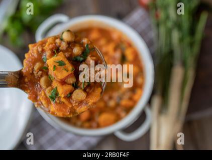 Stufato di ceci con patate dolci e carne su mestolo Foto Stock