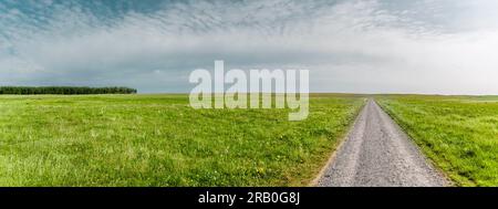 La strada da percorrere attraverso un paesaggio collinare Foto Stock