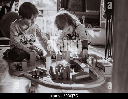 Fratello e sorella giocano con il treno di legno a casa Foto Stock