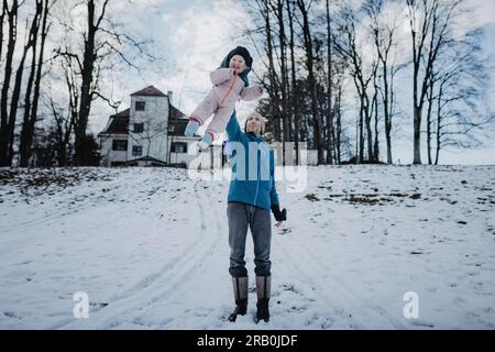 Il padre solleva la figlia in aria con un braccio Foto Stock