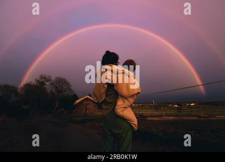 Madre e figlio guardano il doppio arcobaleno Foto Stock