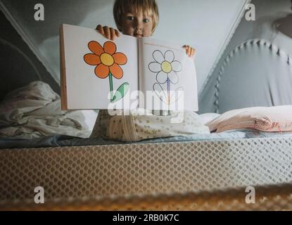 Ragazzo seduto sul letto in camper che mostra un libro da colorare Foto Stock