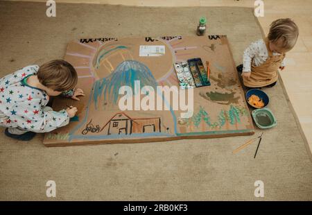 Fratello e sorella dipingono un quadro sul pavimento Foto Stock