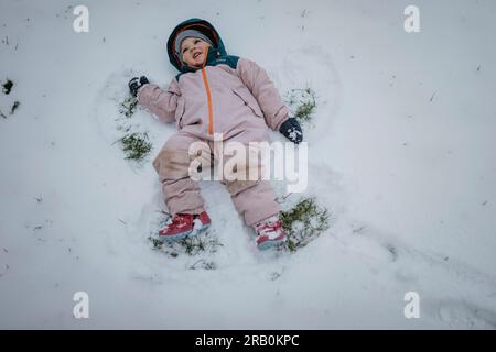 La ragazza fa l'angelo della neve nella neve Foto Stock