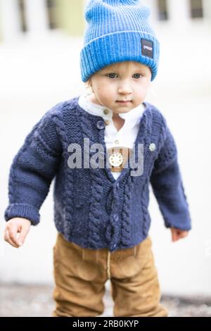 Bambino con pantaloni in pelle, cardigan e berretto in lana Foto Stock