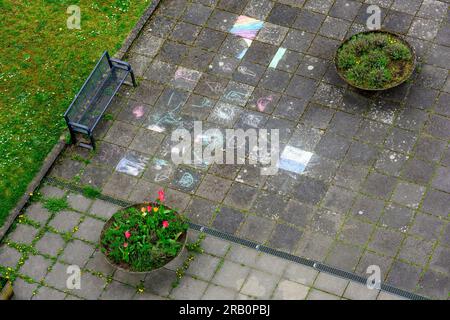 Disegni per bambini dal gesso in un cortile con vasi di fiori. Foto Stock