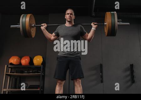 Allenamento sportivo muscoloso e brutale con campanello pesante nella palestra crossfit. Powerlifting, sollevamento pesi, concetto di formazione funzionale. L'atleta CrossFit solleva pesi e fa schiena Foto Stock