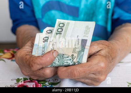 Una donna anziana ha in mano 100 banconote in zloty polacche, denaro polacco, concetto di finanza pensionati Foto Stock