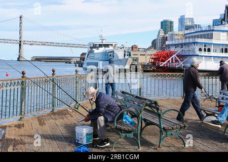 Pesca con canne e lenze alla fine del molo 7 con il battello a vapore Bay Bridge San Francisco Belle e Hornblower Hybrid San Francisco California USA Foto Stock