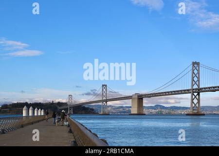 I turisti sul molo 14 con una vista panoramica della baia e del Bay Bridge sull'Embarcadero San Francisco California USA Foto Stock