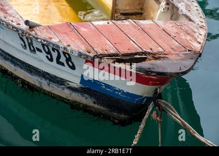 vecchia barca da pesca croata in legno con bandiera dipinta su archi, vecchia barca in legno marcillante, barca a tema nautico in stile squallido ed elegante, barca decadente in rovina. Foto Stock