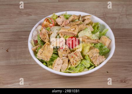 Insalata di pollo Sriracha in ciotola bianca su fondo di legno Foto Stock