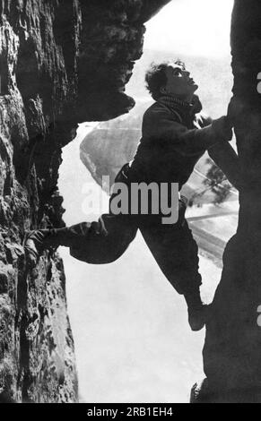 Alpi: c. 1917 stuntman italiano Luciano Albertini che sale su uno stretto crepaccio delle Alpi. Foto Stock