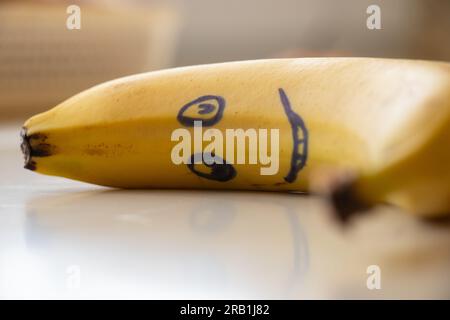 un sorriso viene disegnato su una banana che giace sul tavolo la mattina per la colazione per un bambino Foto Stock